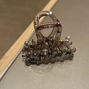 Detailed macro view of gray crystal beads and metallic spring on coffee acrylic hair claw