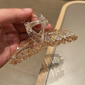 Detail view of large crystal hair claw clip with amber resin stones and golden metal spring