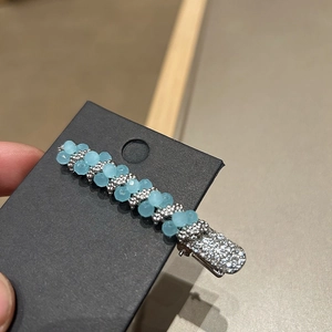Detail of luxury hair clip featuring blue matte beads and rhinestones on a silver base