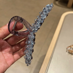 Detailed close-up of a large crystal shark hair clip with purple translucent base and blue gems