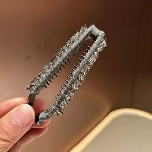 Close-up of hand holding a grey silk banana hair clip with sparkling crystals