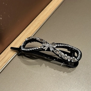 Elegant banana hair clip with sparkling rhinestones and a bow design on a black base