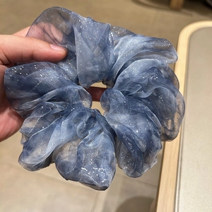 Detail view of large blue organza scrunchie with sparkling silver sequins and star texture