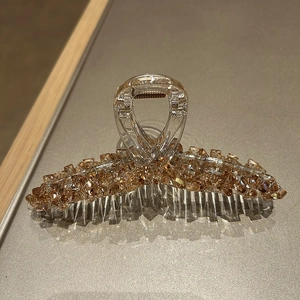 Close-up of luxury champagne crystal hair claw clip with detailed amber gemstone surface