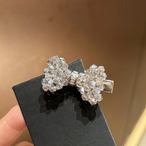 Macro shot of hand-woven crystal bow hair clip featuring sparkling clear beads and metal clip