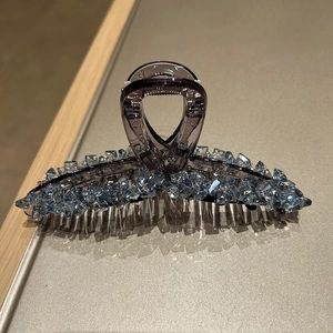 Detailed macro view of large purple hair claw clip with sparkling ice blue crystals