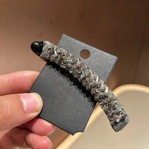 Close-up of elegant banana clip with sparkling grey crystals and silk fabric base