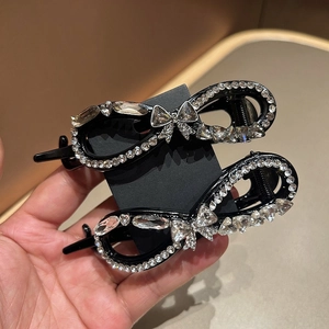 Detail shot of black twisted hair clip with sparkling rhinestones and bow accent