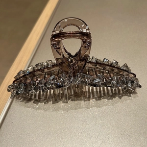 Macro detail of amber large hair claw clip with shimmering crystal rhinestones finish
