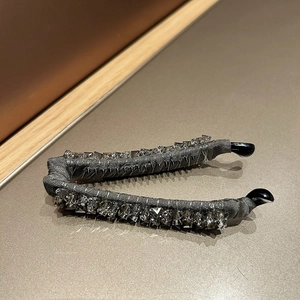 Detail of grey fabric banana clip with square cut crystals on a warm surface