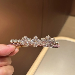 Detailed close-up of crystal flower duckbill hair clip with blue beads and satin wrap