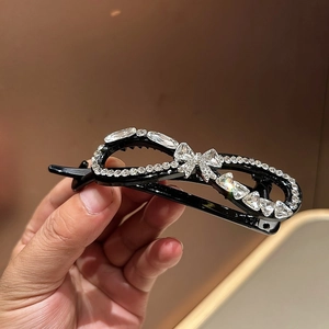 Macro shot of black resin hair claw with rhinestones in an infinity shape and crystal bow