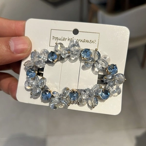 Close-up of handmade crystal hair clip with blue and clear glass beads on display card