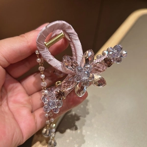 Detail of pink satin hair claw with crystal flower patterns and pearl tassel pendants