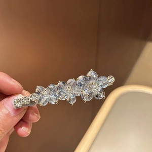 Detail of blue crystal flower hair clip with golden beads and gray texture base