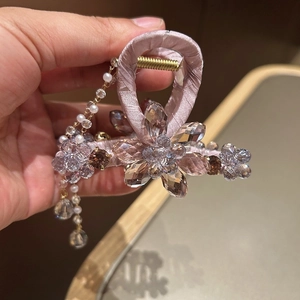 Detail of luxury rhinestone hair claw with lavender satin, crystal flower and pearl tassels