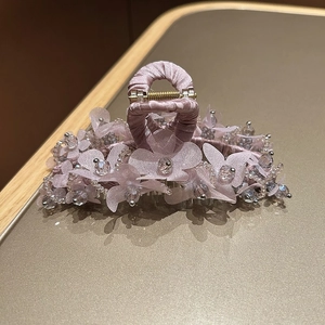 Détail d'une pince à cheveux fleurie lilas avec pétales en organza et perles ciselées