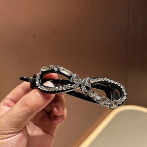 Close-up of black resin hair clip with marquise and pear cut crystals in a bow design