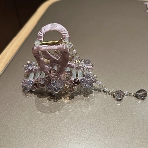 Detail of purple ribbon wrapped crystal hair claw clip with floral beads and tassel