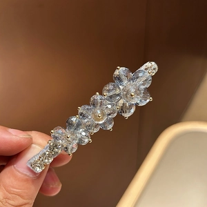 Macro detail of Korean flower hair clip with light blue crystals and golden metal claws
