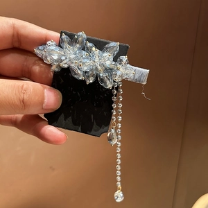 Dettaglio del fermaglio per capelli con fiori in cristallo azzurro e lunghe nappe