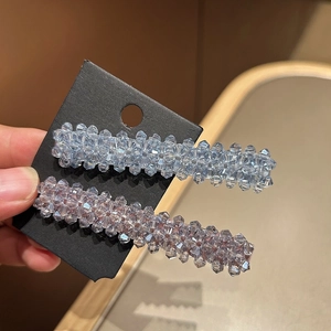 Détail de barrettes en cristal tressé bleu et violet présentées sur une carte noire