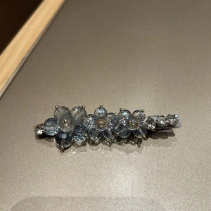 Detailed view of floral blue crystal duckbill clip with clear rhinestones on silver base