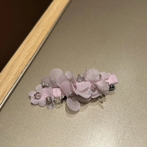 Détail de la pince à cheveux fleur en tissu rose clair avec perles de cristal et paillettes