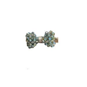 Elegant teal crystal bow hair clip with luxury rhinestone center on a silver metal base