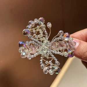 Close-up of handmade crystal floral hair clip with gold wire and beaded fringe detail