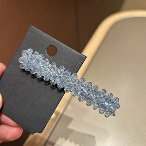 Détail d'une pince à cheveux en perles de cristal bleu clair sur carte noire