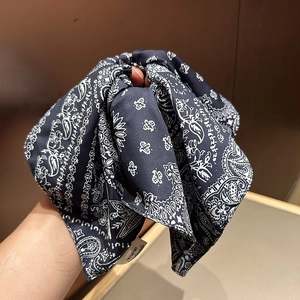 Detail of navy blue paisley pattern scrunchie with a white handmade woven label
