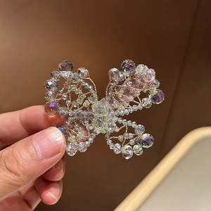 Detailed macro view of handmade gold wire butterfly hair clip with purple crystal beads