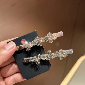 Sparkling crystal hair clips set with pink and grey ribbon base on a black display card