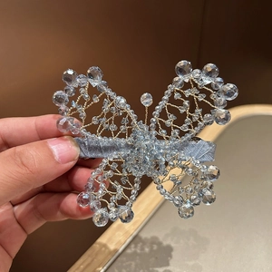 Detail of handcrafted woven butterfly hair clip with sparkling crystal beads and velvet base