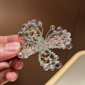 Detail of handmade butterfly hair clip with crystal beads and gold wire on pink base