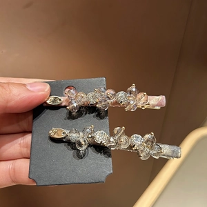 Close-up of handmade beaded hair clips with pink and grey crystals on satin base
