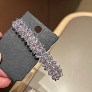 Détail de perles en cristal lavande facettées sur une barrette à ressort métallique