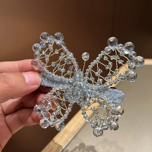 Close-up of handmade crystal butterfly hair clip with gold wire and blue satin detail