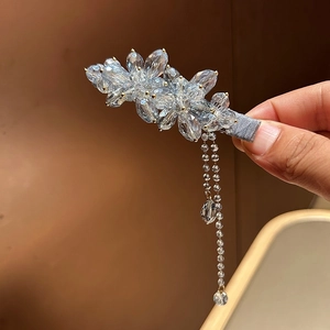 Dettaglio del fermaglio per capelli con fiori di cristallo blu, nappe e base in tessuto