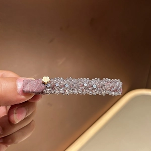 Détail d'une pince à cheveux à perles roses avec fleur dorée et cristaux