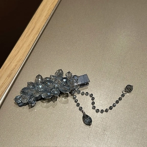 Dettaglio del fermaglio per capelli in cristallo con nappa pendente e gemme blu