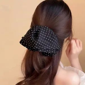 Elegant black and white polka dot satin bow hair clip shown on back of head