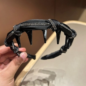 Detail of a black headband with rows of sparkling rhinestones and edgy spikes