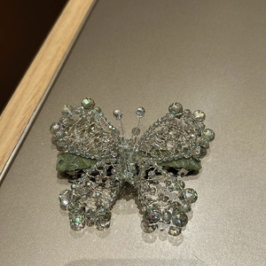 Detail of handmade woven butterfly hair clip with iridescent crystal beads and green satin