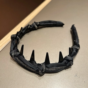 Close-up of black satin headband featuring shimmering rhinestones and punk style spikes