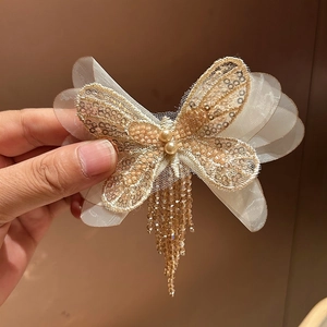 Barrette papillon dorée avec des ailes en résille, des perles et de longs pompons perlés