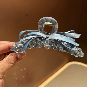 Detailed close-up of a blue ribbon bow hair claw clip with inlaid sparkling crystals