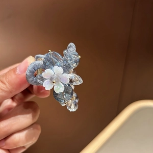 Détail macro de la pince à cheveux fleurie avec perles bleues et ruban gris élégant