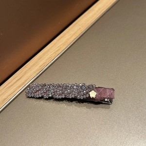 Détail de la pince à cheveux à perles florales en soie violette et décoration florale dorée